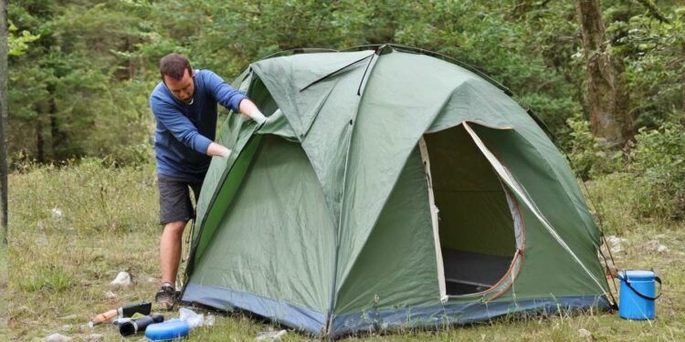 Mann reinigt Campingzelt (NF)