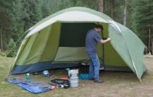 Mann reapariert das Vorzelt vom Campingzelt auf Campingplatz (NF)