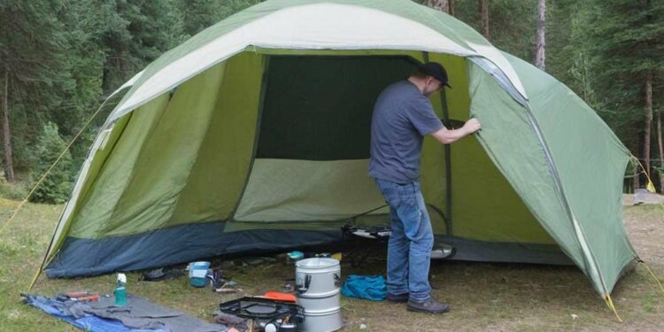 Mann reapariert das Vorzelt vom Campingzelt auf Campingplatz (NF)