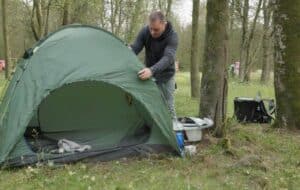 Mann auf Zeltplatz repariert sein Campingzelt (NF)
